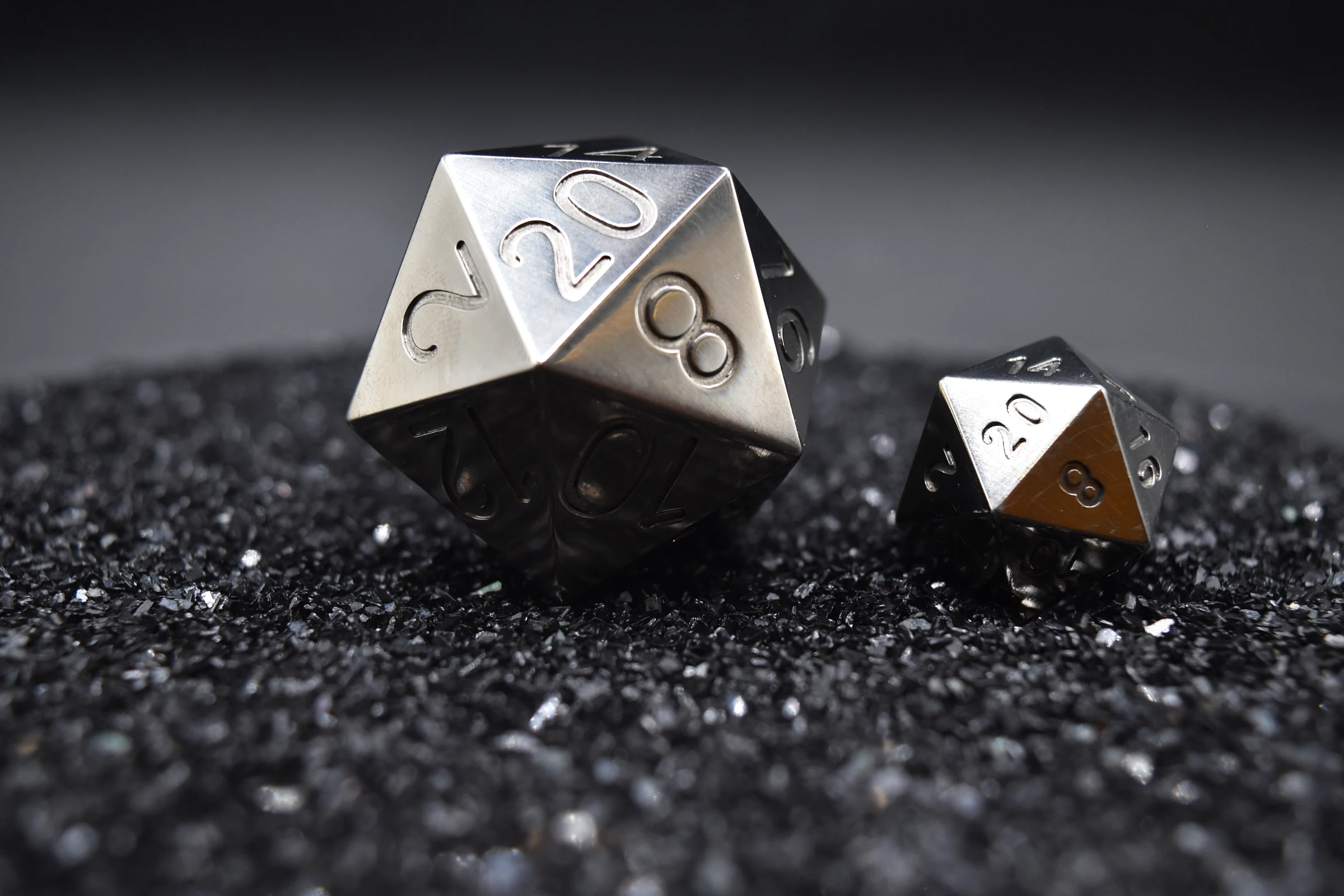 The 35mm titanium Titan beside a standard D20, resting on black grit.