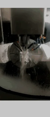 A die blank being cut on a multi-axis CNC mill under coolant.